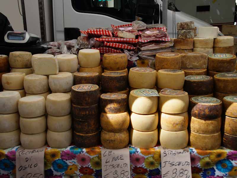 wheels of italian cheeses for sale on a table